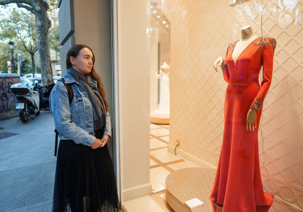 Mağazadaki kırmızı elbiseyi hayal eden kadın - Fotoğraf, Görsel