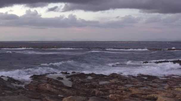 Akdeniz 'de dalgalarla birlikte Mallorca adasının kayalık sahillerinde rüzgarlı bir sonbahar gününde gün batımı. Muhteşem manzara. - Video, Çekim