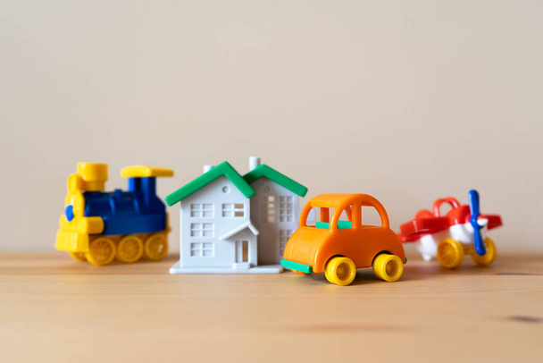 Closeup image of house, car, airplane and train figure models on the wooden table. Property and vehicle insurance - Fotó, kép