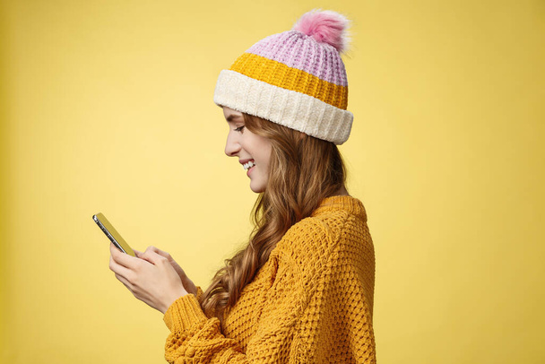 Profile shot charming outgoing relaxed young modern millennial girl texting smiling broadly holding smartphone looking display amused editing pic post online, blogger messaging followers - Foto, immagini