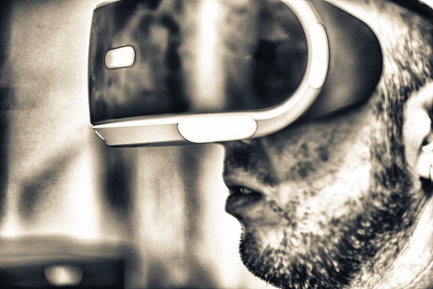Πλευρική άποψη του ανθρώπου που παίζει με το προσωπείο VR. - Φωτογραφία, εικόνα