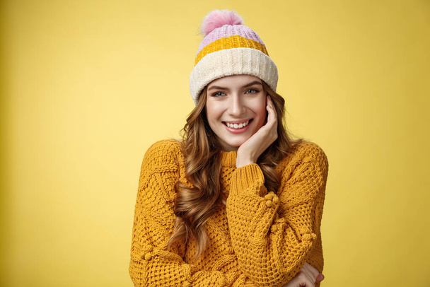 Мрійлива ніжна романтична жінка в теплому капелюсі, в'язаний светр, посміхаючись, кокетливо спокушає вас, виглядає зацікавленою щасливою, худорлявою долонею, слухаючи цікаву історію, жовтий фон
 - Фото, зображення