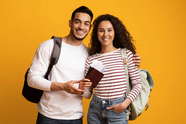 Vrolijke Reizigers. Lachend Arabisch paar met rugzakken, paspoorten en reistickets - Foto, afbeelding