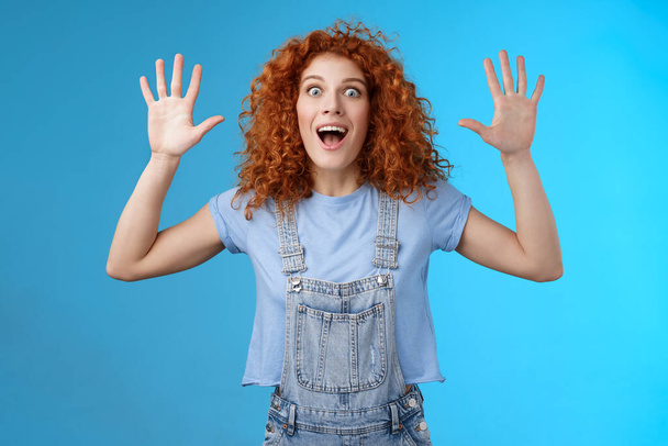 Excited crazy playful funny redhead curly emotive girl yelling carefree raise hands surrender up open mouth fool around smiling broadly stare camera joyful express wild daring emotions - Foto, Imagen
