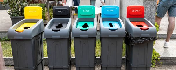 Σειρά από πολλά διαφορετικά πολύχρωμα πλαστικά δοχεία απορριμμάτων για διαλογή και ανακύκλωση απορριμμάτων στο δρόμο της πόλης σε εξωτερικούς χώρους. Προστασία του περιβάλλοντος και πρόληψη των κινδύνων από τη ρύπανση της φύσης - Φωτογραφία, εικόνα