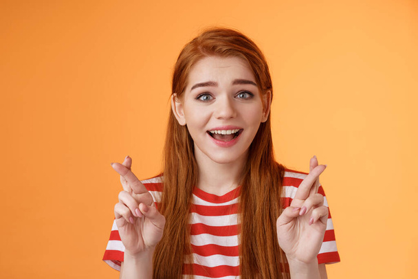 Excited hopeful redhead girl hope win lottery, smiling optimistic, look faith, believe dream come true, cross fingers good luck, make wish, anticipate good news, praying fortune, orange background - Fotoğraf, Görsel