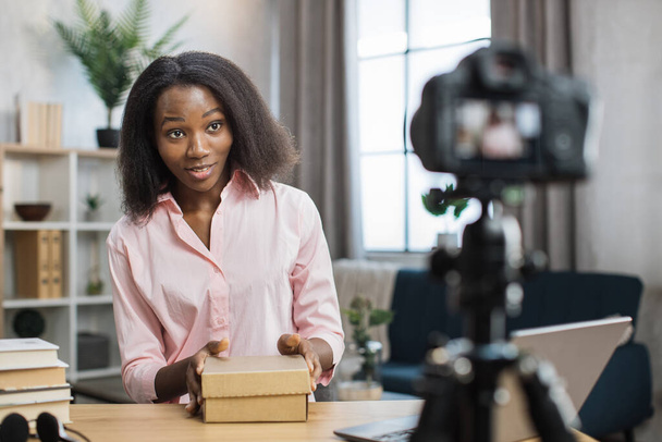 African woman recording video blog while opening parcel box - Photo, Image