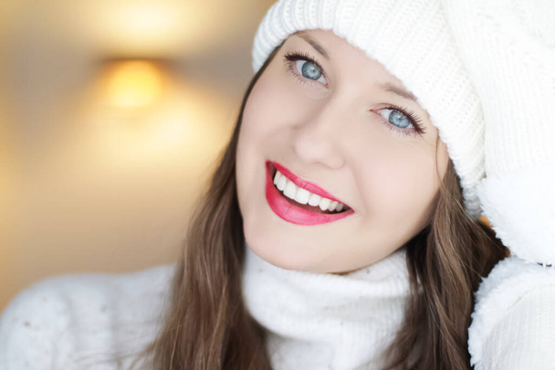 Kerstmis, mensen en winter vakantie concept. Gelukkig lachende vrouw draagt witte gebreide hoed als close-up gezicht xmas portret - Foto, afbeelding