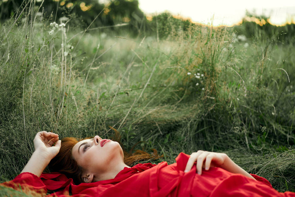 pretty woman in red dress lies on the grass freedom landscape - Фото, изображение