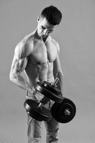 Desarrollo de fuerza y músculo bíceps del brazo. Un tipo fuerte levanta pesas. Entrenamiento de entrenamiento de fuerza - Foto, imagen