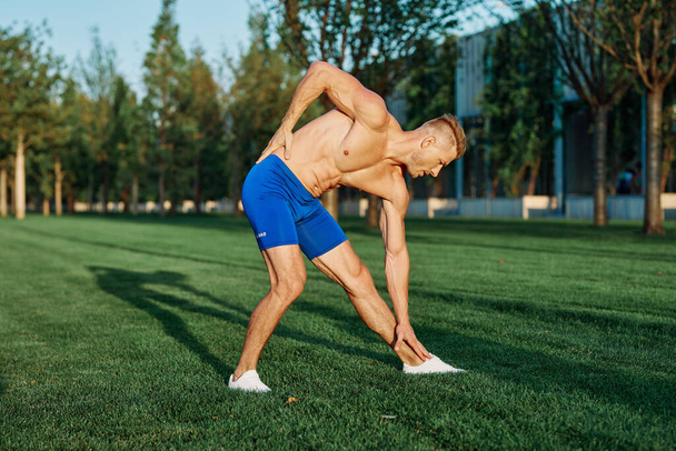 man with muscular body exercising in summer park - Фото, зображення