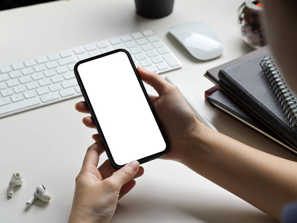 Schnappschuss einer Geschäftsfrau oder einer Frau mit leerem Bildschirm-Smartphone in einem modernen weißen Büroarbeitstisch. - Foto, Bild