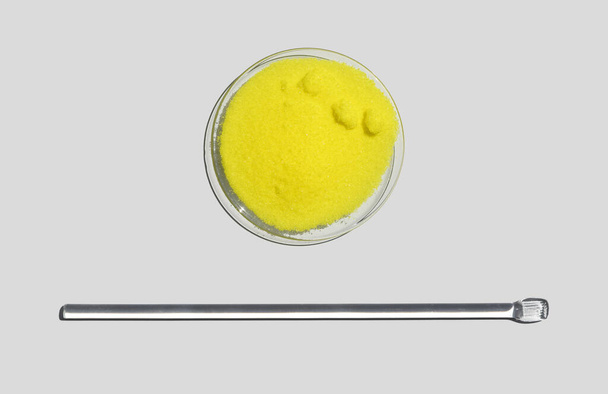 Kaliumkromaattijauhe kemiallisessa kellonlasissa sekoitustangon vieressä. lähikuva kemiallinen ainesosa valkoisessa laboratoriopöydässä. Ylhäältä - Valokuva, kuva