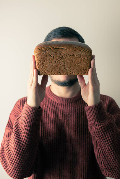 A man holds a loaf of homemade rye bread. - Foto, immagini
