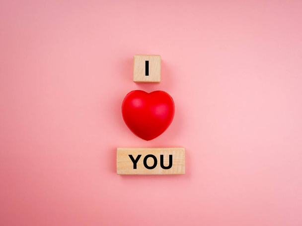 Я люблю тебе, текст на дерев'яному кубі та червона серцева куля на рожевому пастельному фоні. Концепція любові мінімальний стиль
. - Фото, зображення