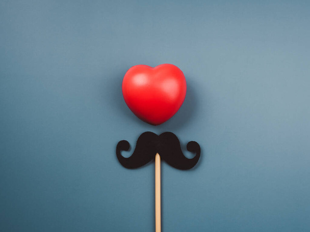 Kırmızı kalp topu ve bıyık, mavi arka planda izole edilmiş, minimal stil. Mutlu Babalar Günü, Movember konsepti.  - Fotoğraf, Görsel