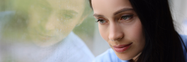 Smutná unavená žena se dívá z okna, když prší detailní záběr - Fotografie, Obrázek
