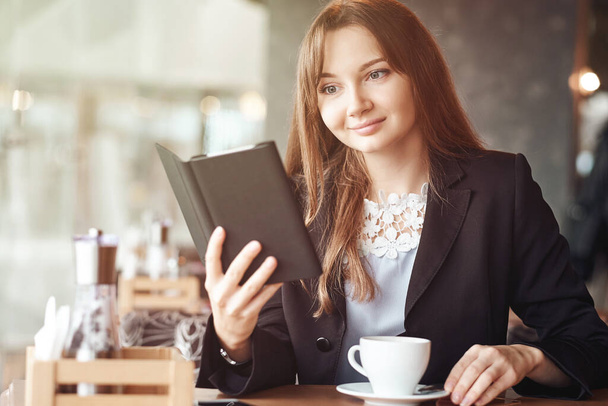 Mladá žena v kavárně čtení ebook a pití kávy. - Fotografie, Obrázek