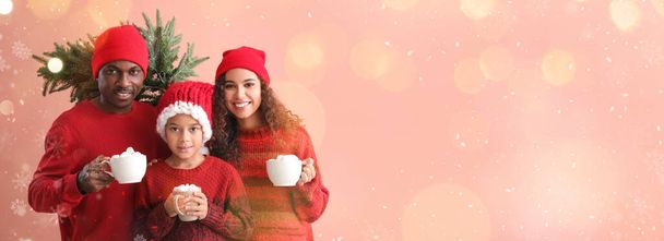 Africko-americká rodina v zimním oblečení, s chutnou horkou čokoládou a vánoční stromeček na barevném pozadí s prostorem pro text - Fotografie, Obrázek