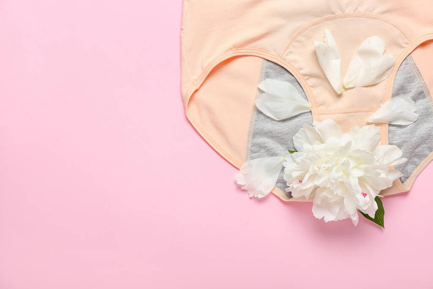Period panties and beautiful peony flower on color background, closeup - Zdjęcie, obraz
