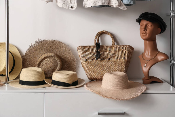 Манекен с кожаной кепкой, различные соломенные шляпы и сумки на полке в шкафу - Фото, изображение
