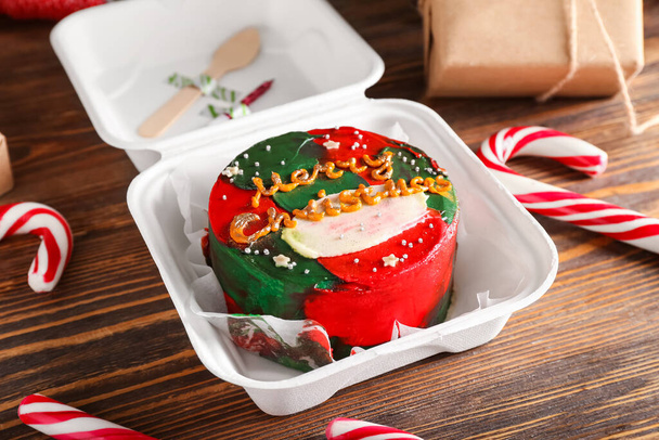 Пластикова обідня коробка з різдвяним пирогом на дерев'яному фоні, крупним планом
 - Фото, зображення