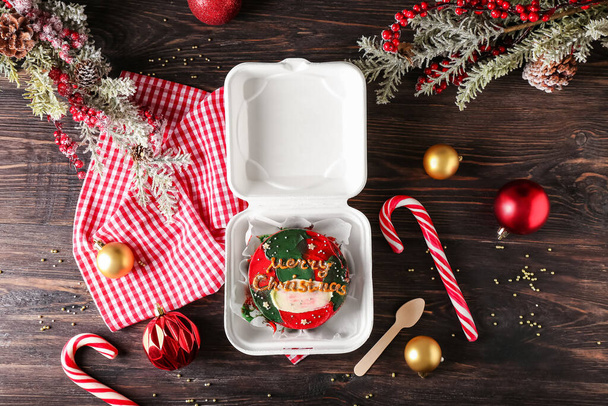 Пластикова обідня коробка зі смачним тортом Бенто та різдвяним декором на дерев'яному фоні
 - Фото, зображення