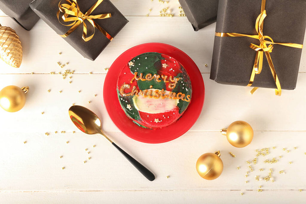 Lemez ízletes bento torta, ajándékok és karácsonyi labdák világos fa háttér - Fotó, kép