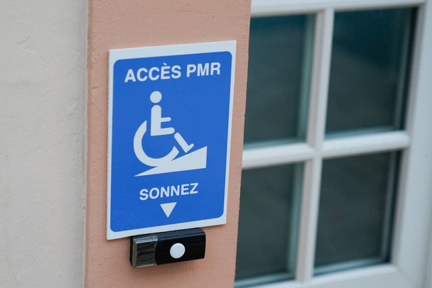 disabled accessible arrow entry sign post with wheelchair handicap logo pmr means  people someone with reduced mobility on wall entrance store access pictogram on street shop - Foto, Bild