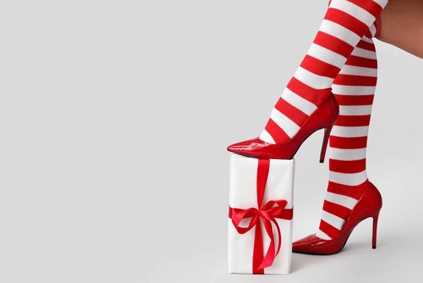 Sexy giovane donna in calze di Natale e con regalo su sfondo chiaro - Foto, immagini