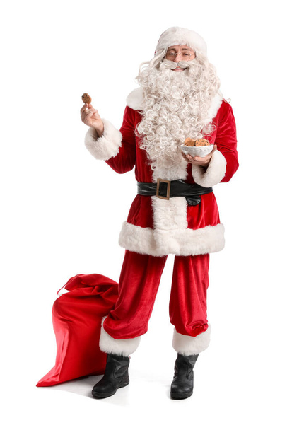 Papai Noel com biscoitos saborosos e saco no fundo branco - Foto, Imagem