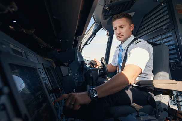 Man first officer pressing button on airplane control panel - Zdjęcie, obraz