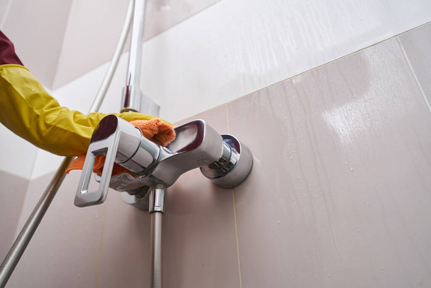 Professional cleaner cleaning plumbing fixture in bathroom - Фото, изображение