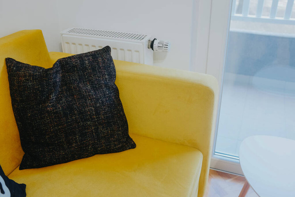 A closeup shot of a black pillow on a yellow sofa - Фото, зображення