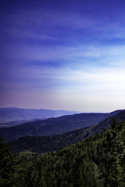 A landscape of forested mountains under the blue sky - Fotó, kép