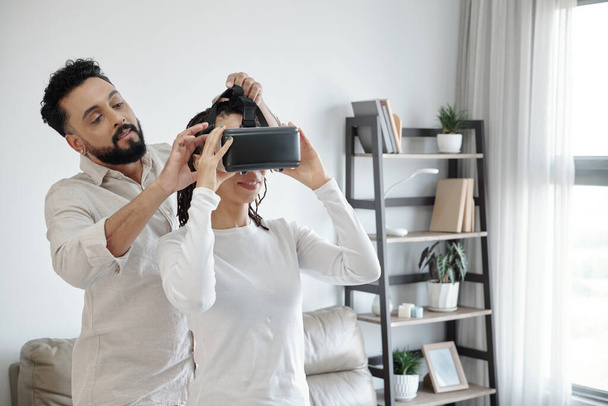 Homem ajudando namorada a usar fone de ouvido VR - Foto, Imagem