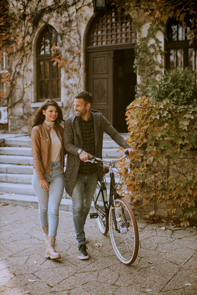Jóképű fiatal pár séta kerékpárral az őszi parkban - Fotó, kép
