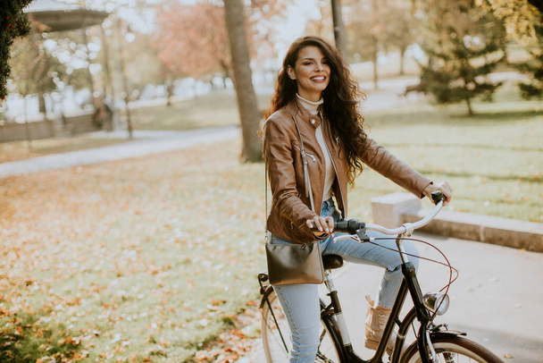 Pretty young woman riding bicycle on autumn day - Foto, imagen
