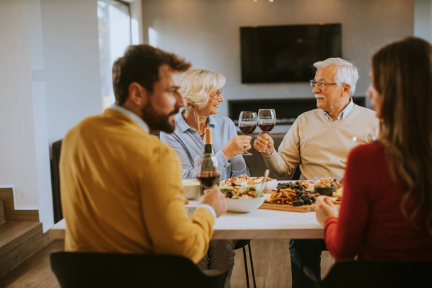 Heureuse famille qui dîne avec du vin rouge à la maison - Photo, image
