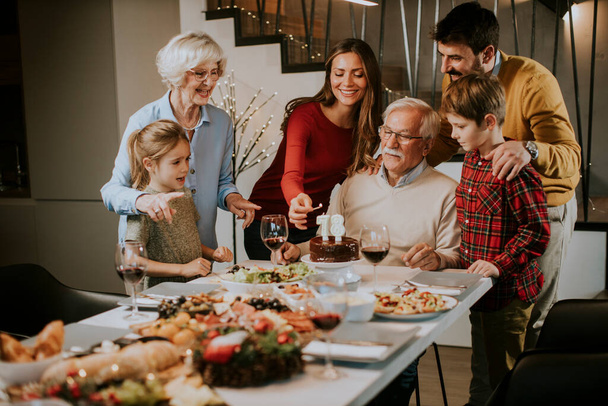 Glückliche Familie feiert Opa-Geburtstag mit Kuchen und Kerzen zu Hause - Foto, Bild