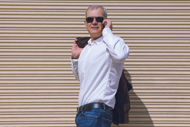 elegant mature man talking with mobile phone with blind background - Photo, image