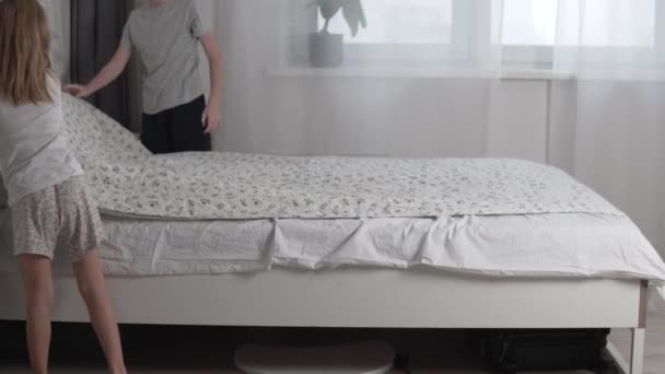 Niños, un niño y una niña, limpian la cama de sus padres por la mañana - Metraje, vídeo