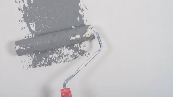 Painting the wall with a roller in gray during the repair. - Foto, Bild