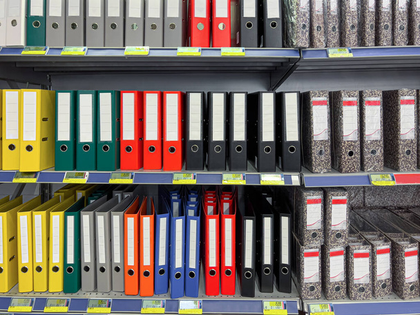 Archivos multicolores y carpetas con etiquetas en blanco que se muestran en el estante de la tienda. - Foto, Imagen