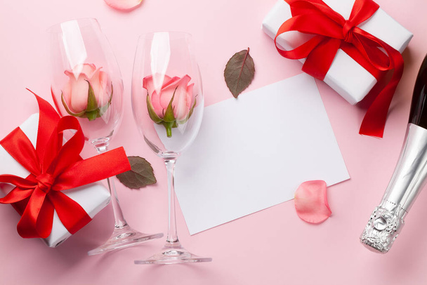 Kieliszki szampana, pudełko z prezentami i płatki kwiatów róż. Walentynki kartka z życzeniami z miejsca na pozdrowienia. Widok z góry płaski lay - Zdjęcie, obraz