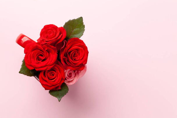 Rozenbloemen in koffiekopje. Valentijnsdag wenskaart met ruimte voor uw groeten. Bovenaanzicht vlak lay - Foto, afbeelding