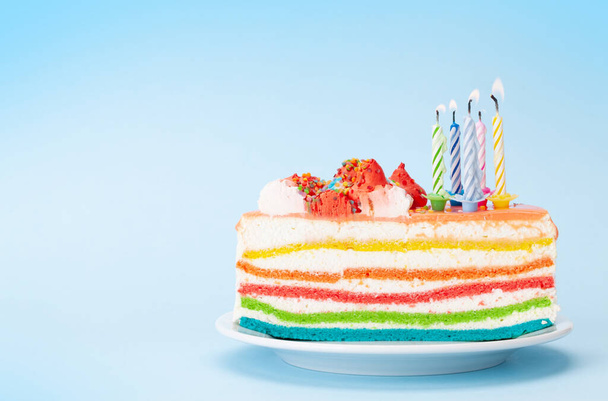 誕生日や休日のケーキあなたの挨拶のためのコピースペースと青の背景に燃えるろうそく - 写真・画像