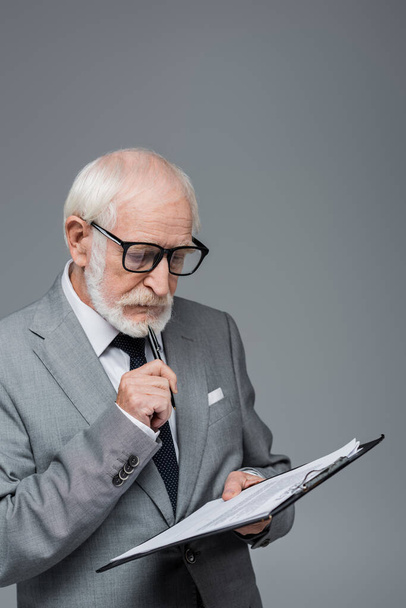 στοχαστικός ανώτερος επιχειρηματίας σε γυαλιά ηλίου σύμβαση ανάγνωση απομονώνονται σε γκρι - Φωτογραφία, εικόνα
