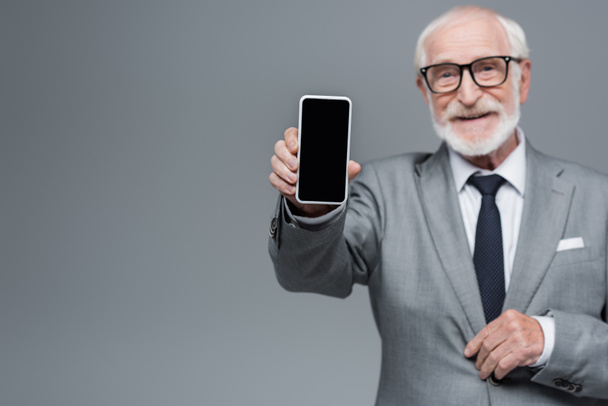 homályos vezető üzletember mutatja mobiltelefon üres képernyő elszigetelt szürke - Fotó, kép
