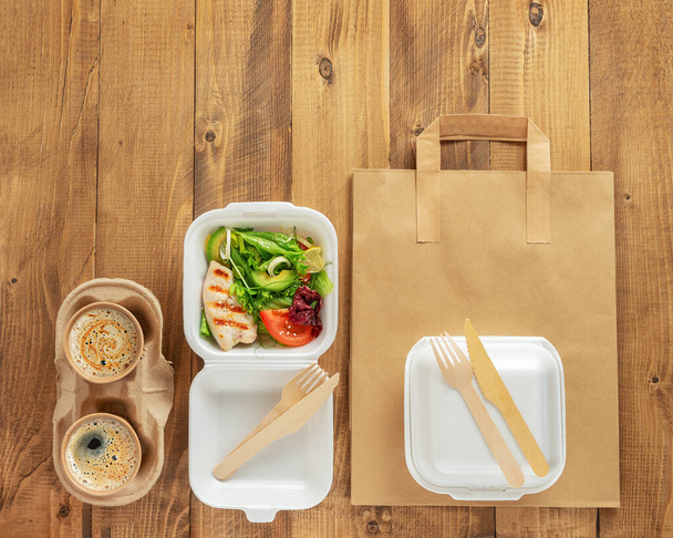 Healthy food delivery. Fresh salad with chicken and coffee on wooden background. Top view, copy space. - Photo, Image